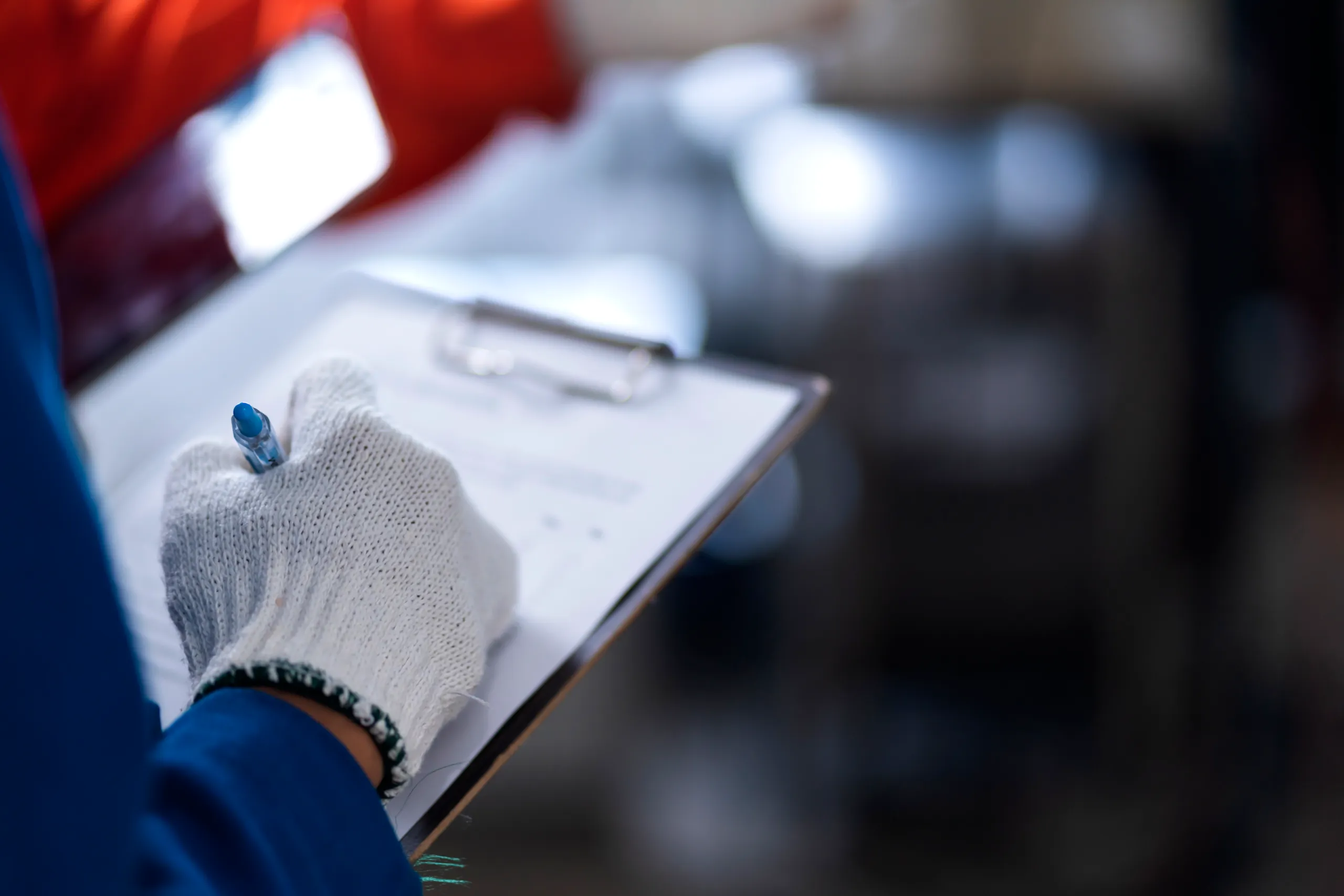 Addetto con guanti da lavoro compila checklist di certificazione su clipboard – Bando certificazioni PMI Friuli Venezia Giulia 2025