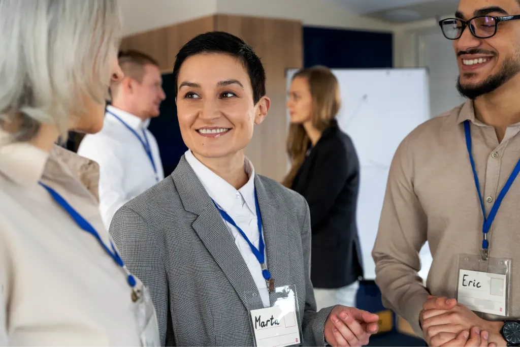 Partecipanti sorridenti con badge al collo durante un evento fieristico e di networking
